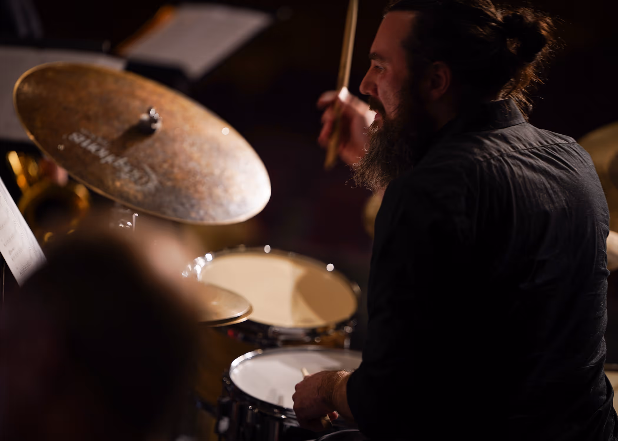Drummer laughing mid-groove behind the cymbals